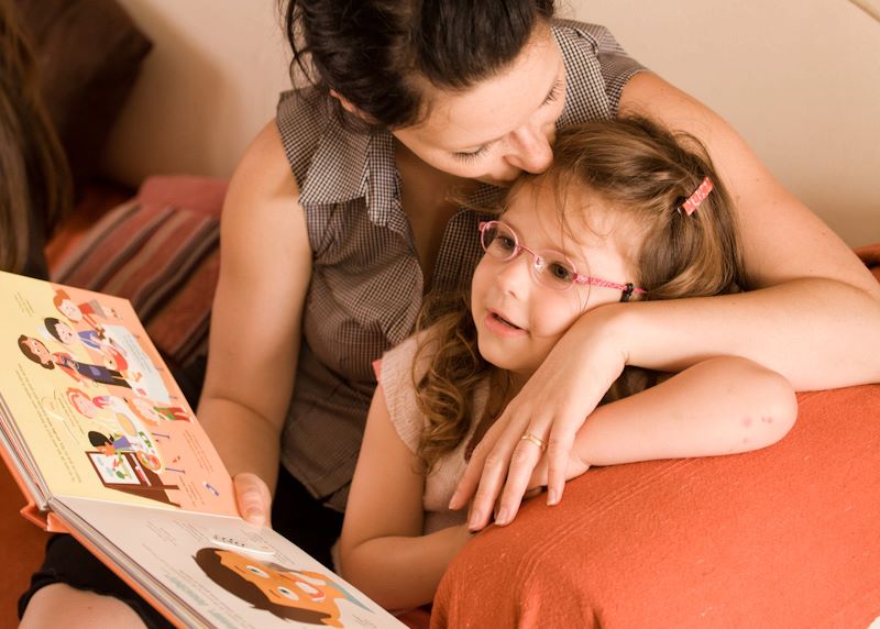 Mère lisant un livre avec sa fille, elles sont heureuses