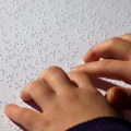 enfant qui lit un texte en braille UNE