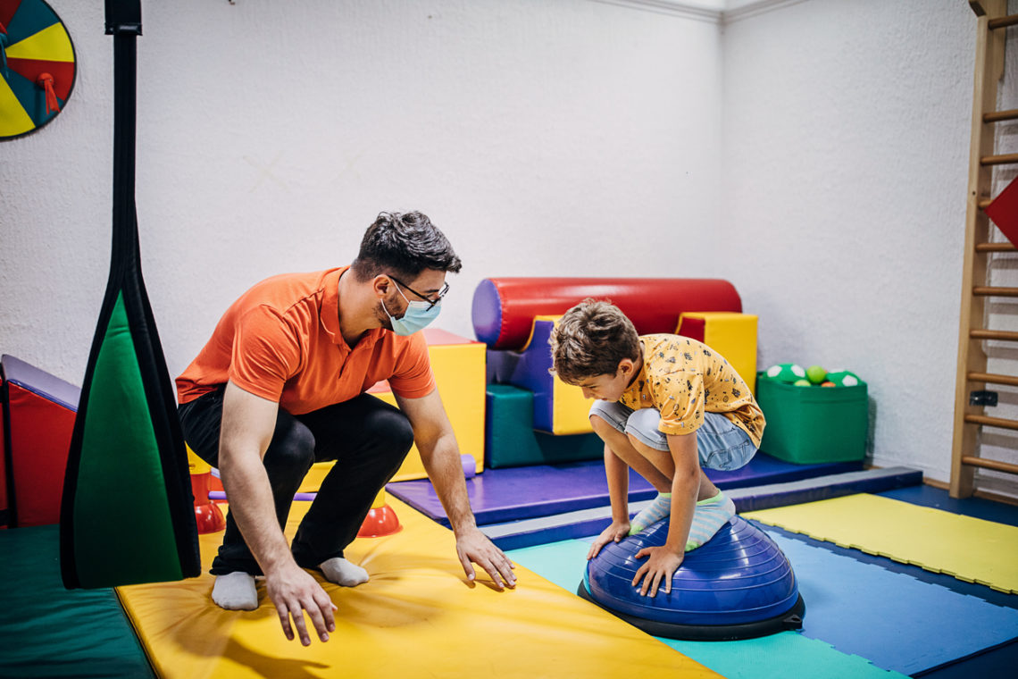 Enfant garçon qui s'exerce avec son psychomotricien Istock