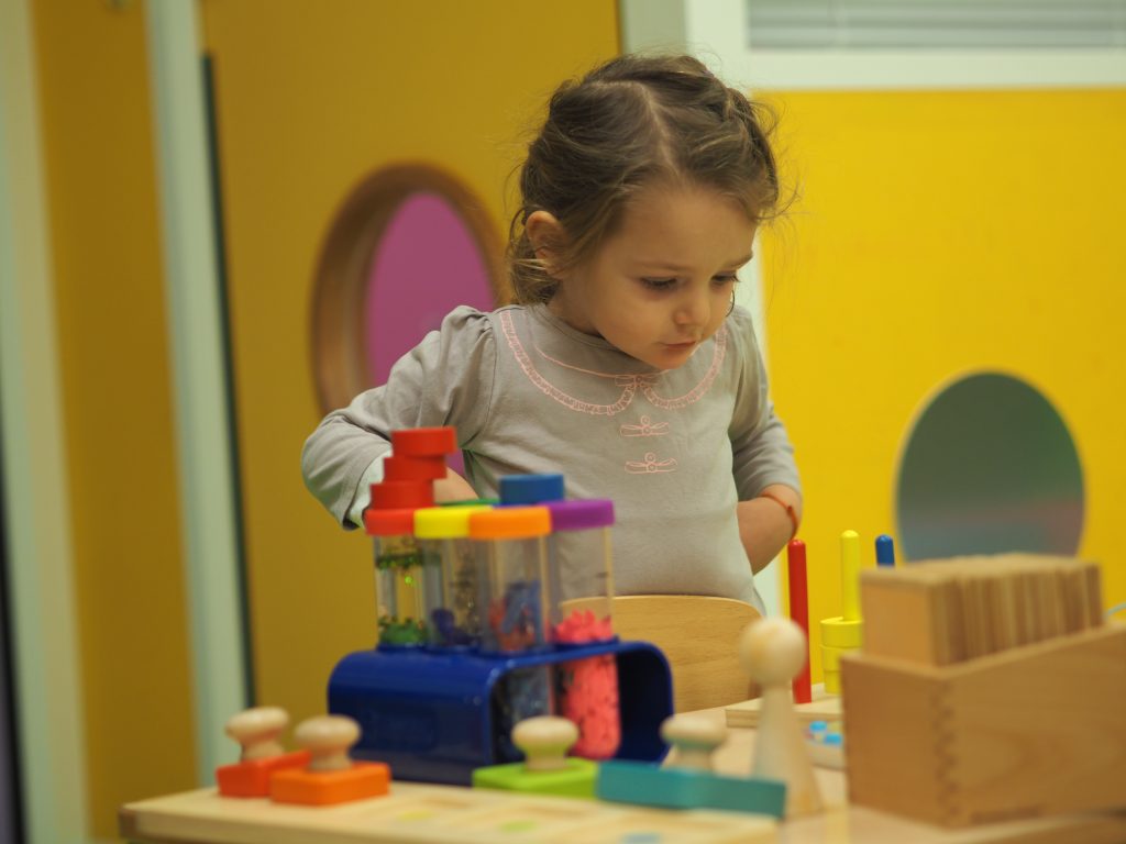 Une fille devant divers jeux et objets sensoriels