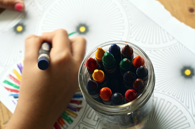 Un enfant dessine avec des crayons.