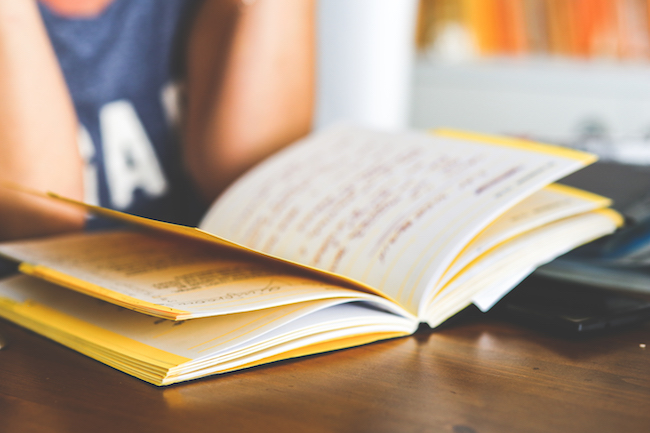 Un enfant lit un livre posé sur un bureau