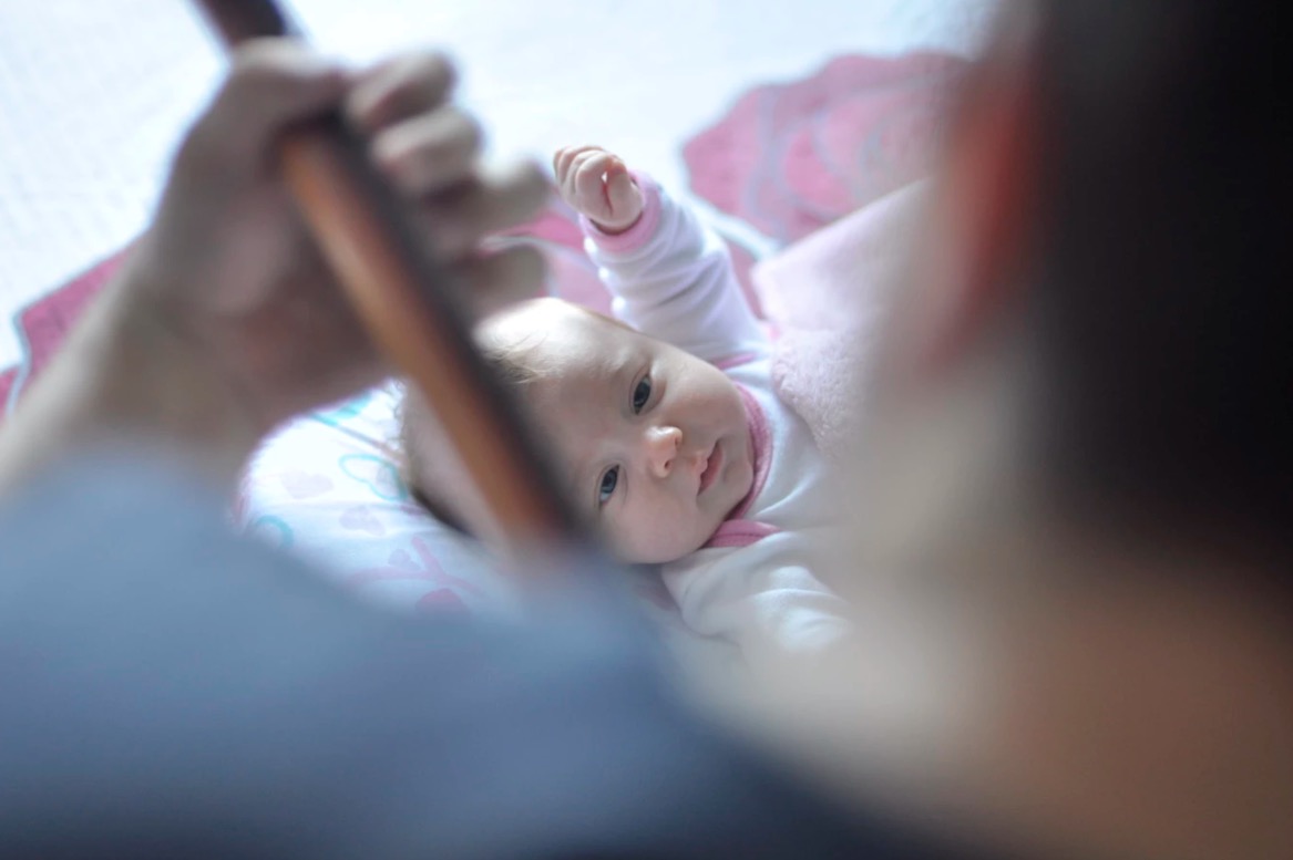 Une personne joue d'un instrument à un bébé. Le développement du langage par la musique.