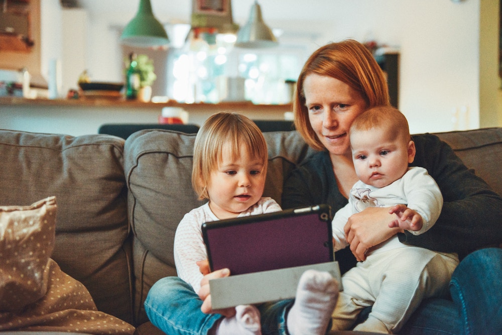 Une mère et ses deux enfants devant un écran de tablette.