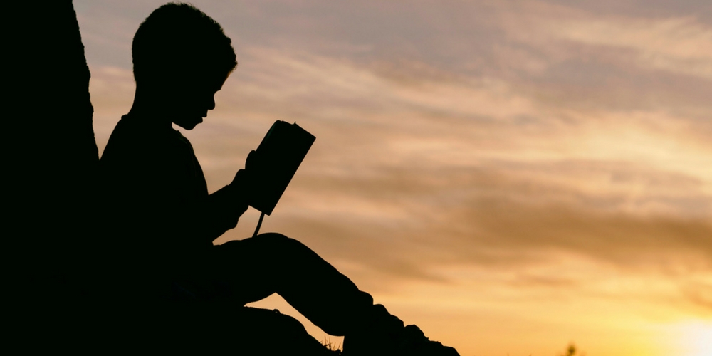 Un enfant lit un livre la nuit