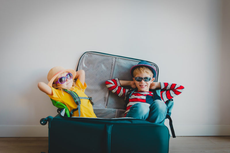 2 enfants heureux assis dans une valise.