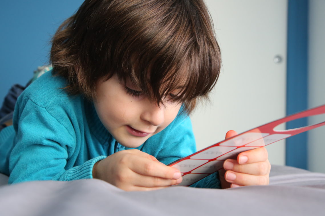 Un enfant tient dans sa main un support de communication pour pictogrammes aimantés Idéo Picto.