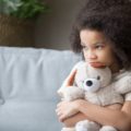 Une petite fille serre un ours en peluche dans ses bras