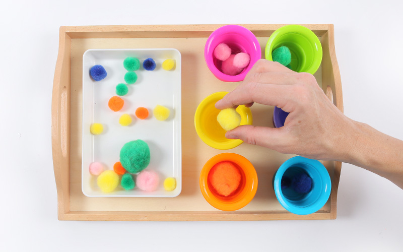 Plateaux Montessori : un plateau avec des pompons et des gobelets colorés pour apprendre les couleurs