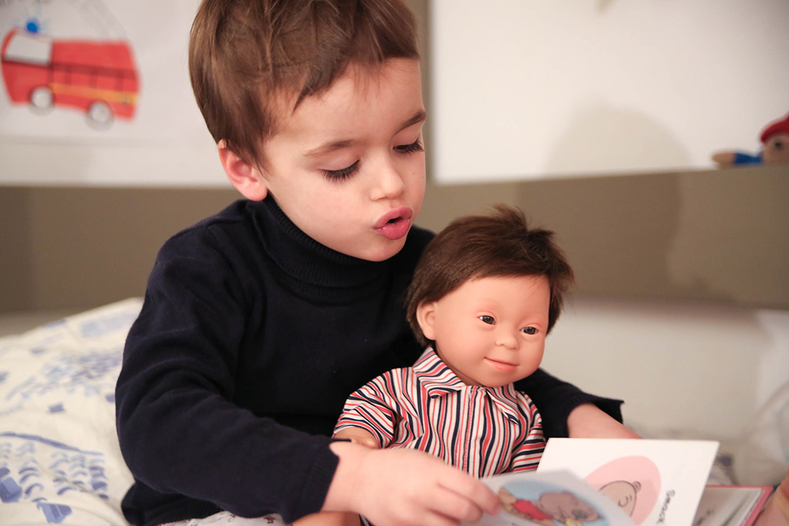 Un enfant lit avec un poupon dans ses bras