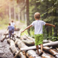 Enfant en équilibre sur rondin de bois dans la forêt. Petit aventurier