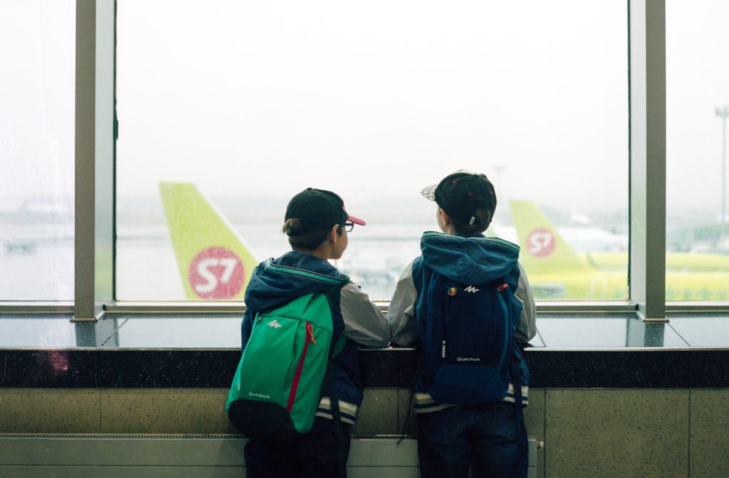 deux enfants regardent un avion au loin