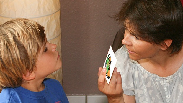 Langage : Une femme communique avec un enfant à l'aide d'un pictogramme représentant une chaussure.