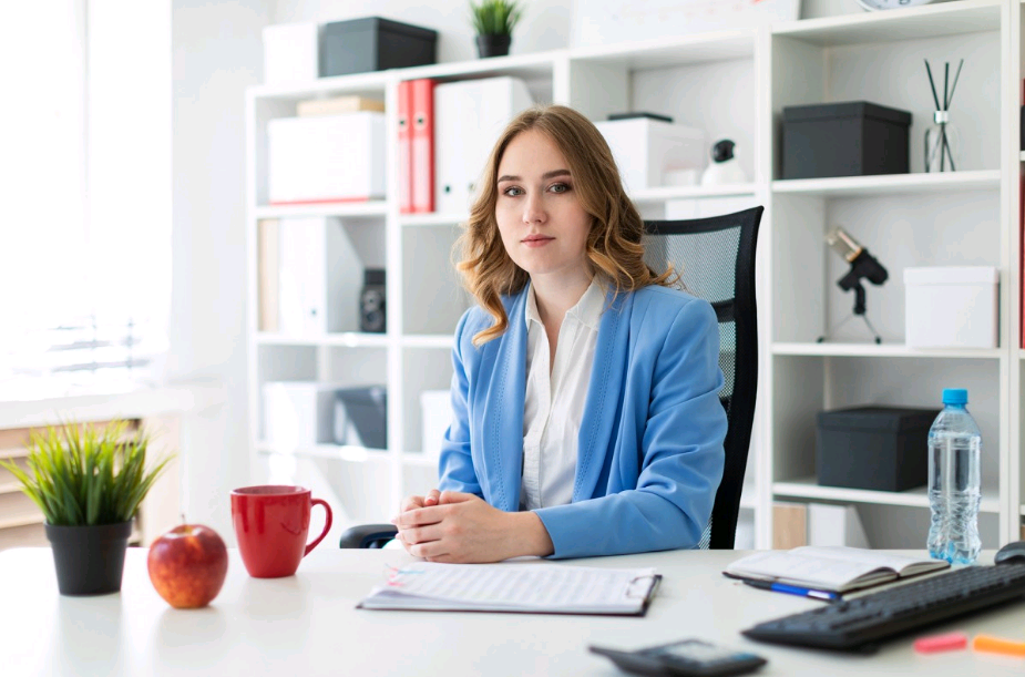 Une femme portant une veste de tailleur bleue assise à un bureau.