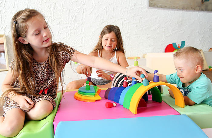 Des enfants jouent avec des jeux invitant à la libre exploration. Les arcs en bois de différentes couleurs deviennent des ponts.