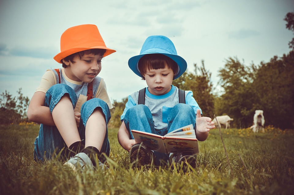 Deux enfants lisent un livre sur l'herbe