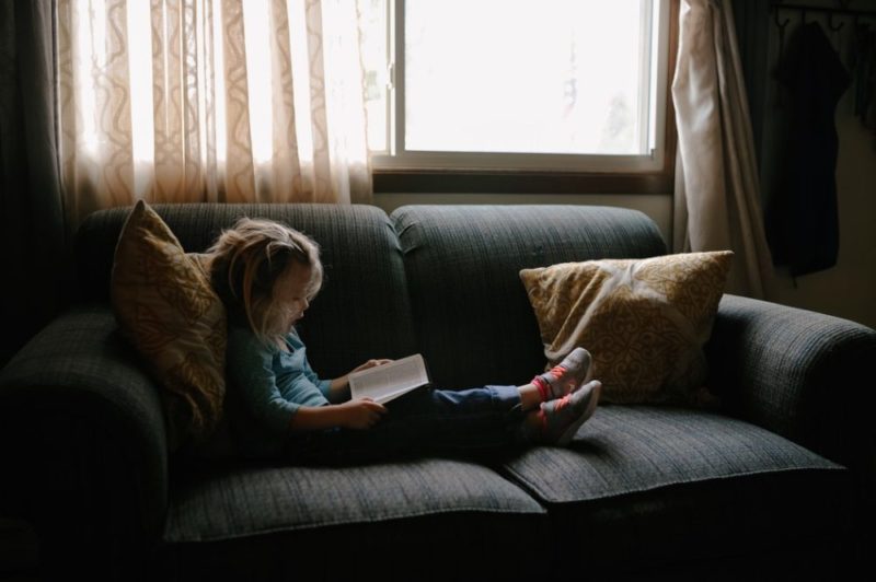 Les bienfaits de la lecture, petite fille lisant sur le canapé