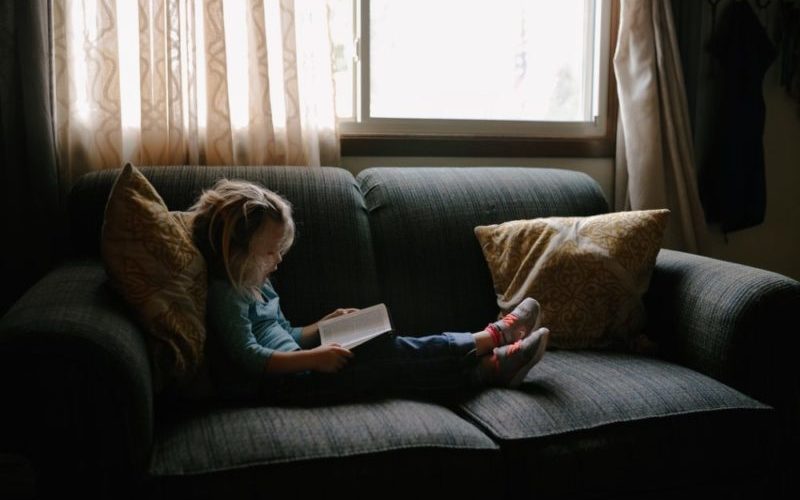 Les bienfaits de la lecture, petite fille lisant sur le canapé