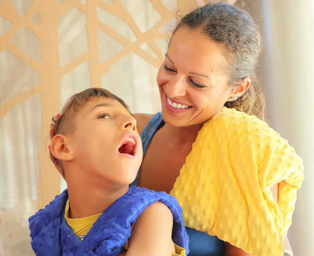 Enfant polyhandicapé qui teste différents coussins sensoriels.