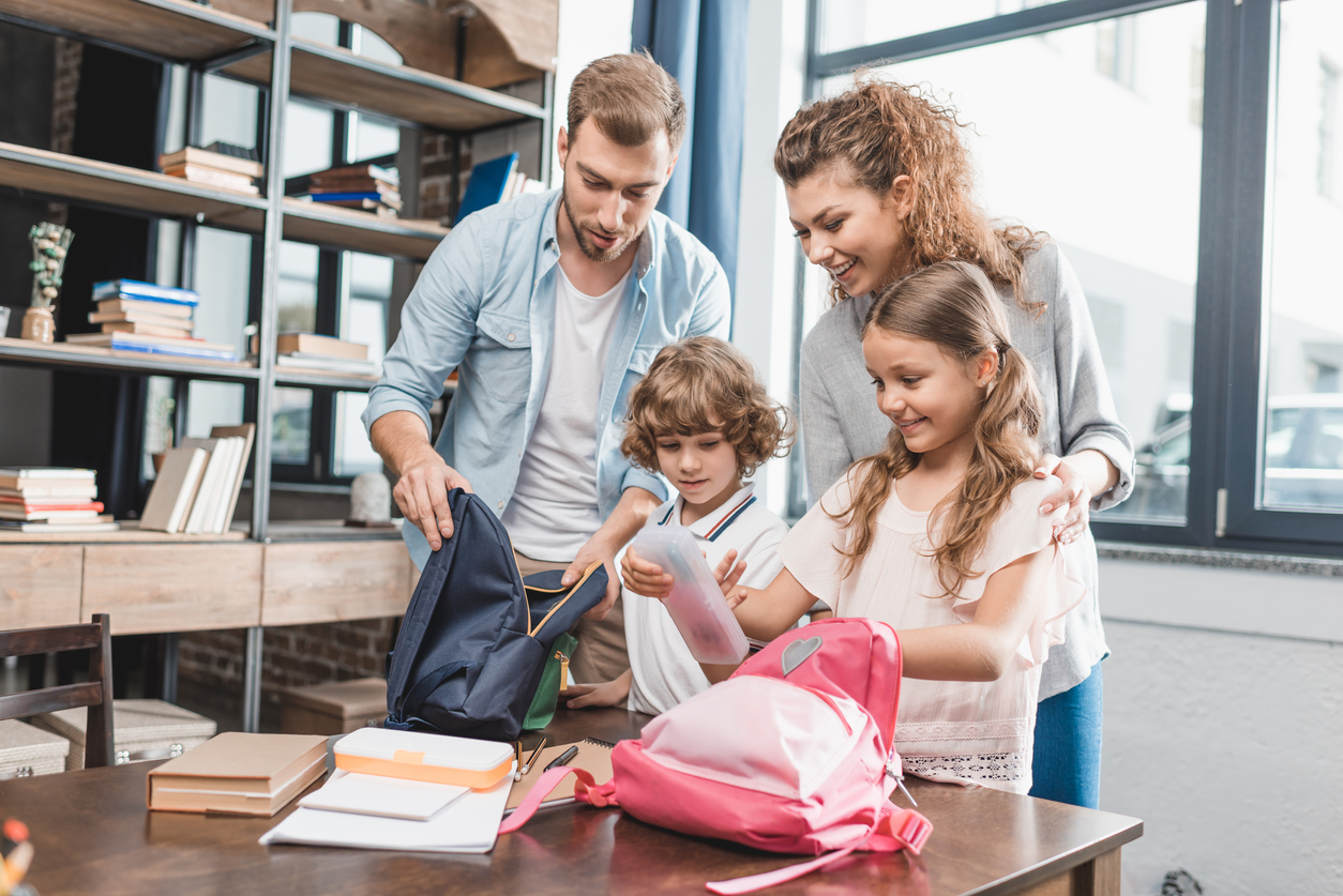 Des parents préparent les sacs pour l'école avec leurs enfants pour la rentrée