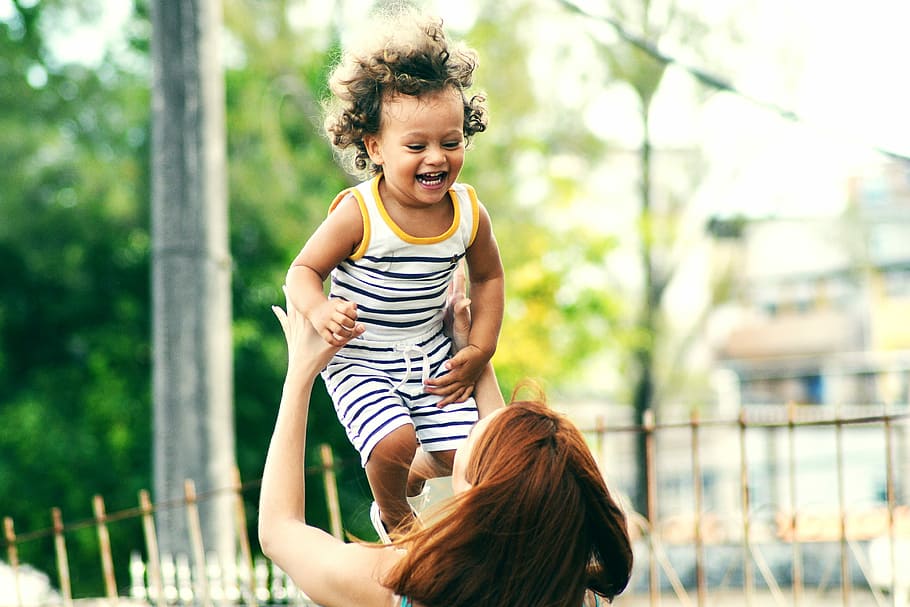 Une maman lance dans les airs un jeune enfant qui rit.