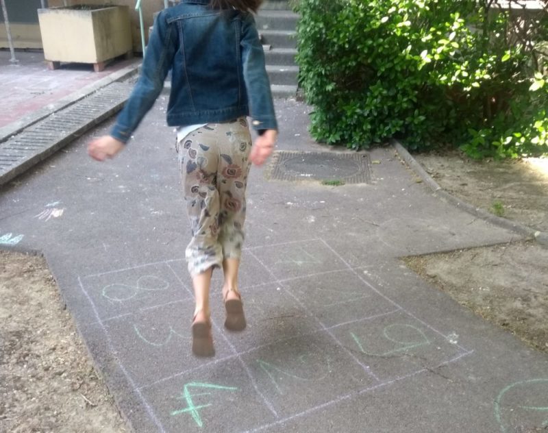 Enfant qui saute sur un cadran numérique dessiné à la craie sur le sol