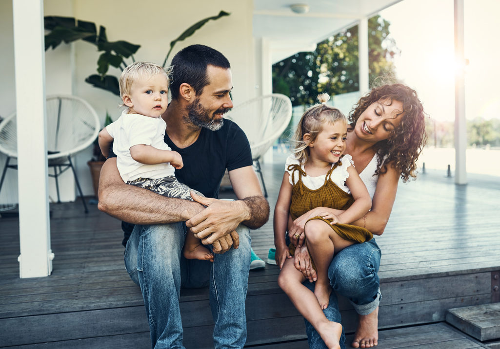 Famille assise devant une maison sur des marches.