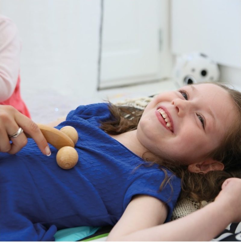 Une enfant polyhandicapé reçoit un massage grâce à un outils du panier de massage