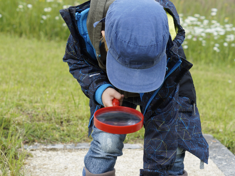 Un enfant joue avec une loupe à l'extérieur