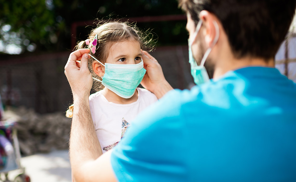 Un homme place un masque sur le visage d'une petite fille.