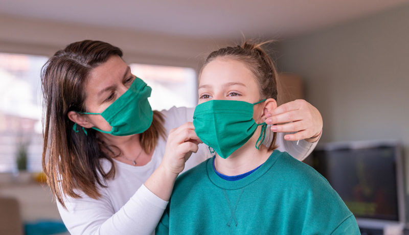 Une mère aide son enfant à placer son masque sur son visage