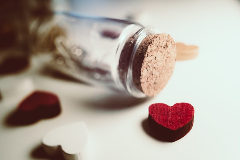 Une petite bouteille en verre et des cœurs en bois