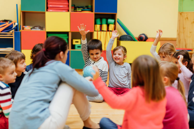 Des enfants assis au sol autour de l'enseignante en classe flexible.