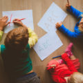 enfants qui dessinent allongés sur le sol