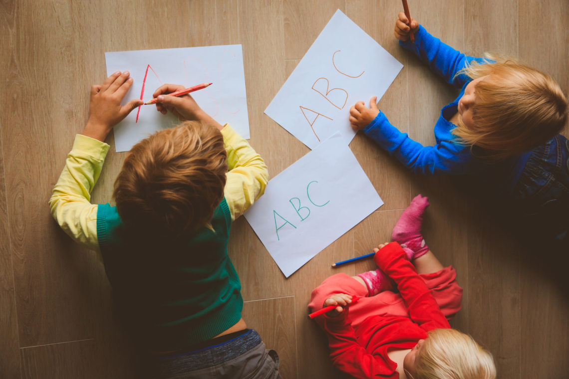 Enfants qui dessinent allongés sur le sol