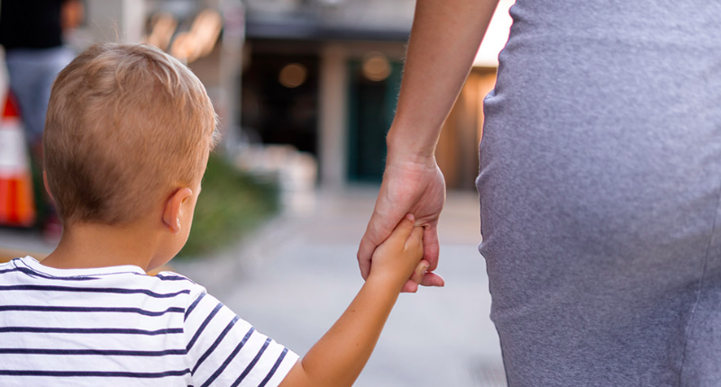 Un enfant tient la main de sa maman