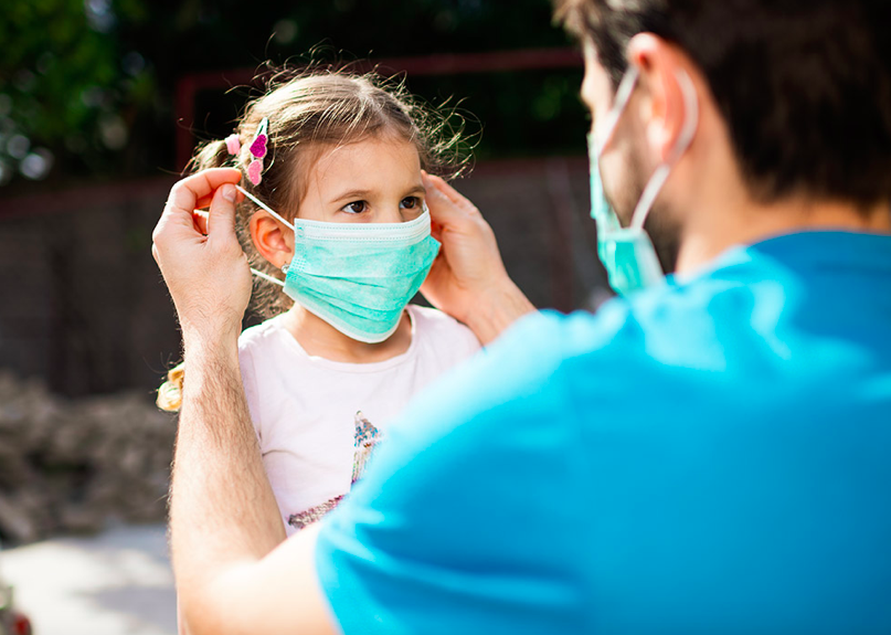 Un père qui met un masque à son enfant