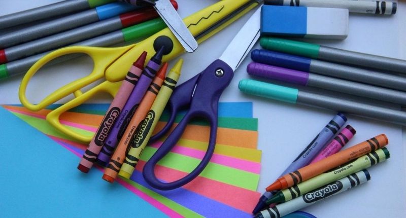 Des ciseaux, des crayons, des stylos et des feuilles colorées sur un bureau