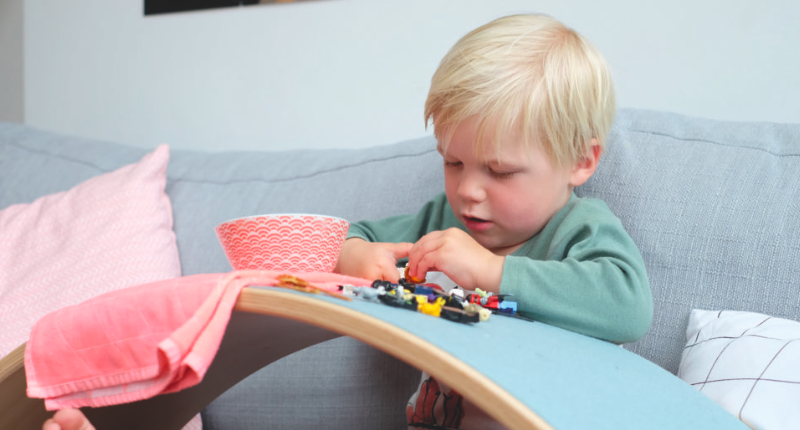 Un enfant qui utilise la planche Wobbel comme une table pour jouer.