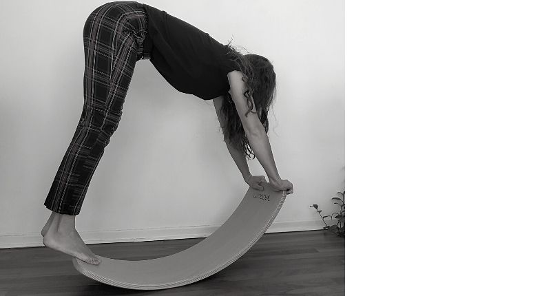 Une femme en position "chien tête en bas" sur une planche Wobbel