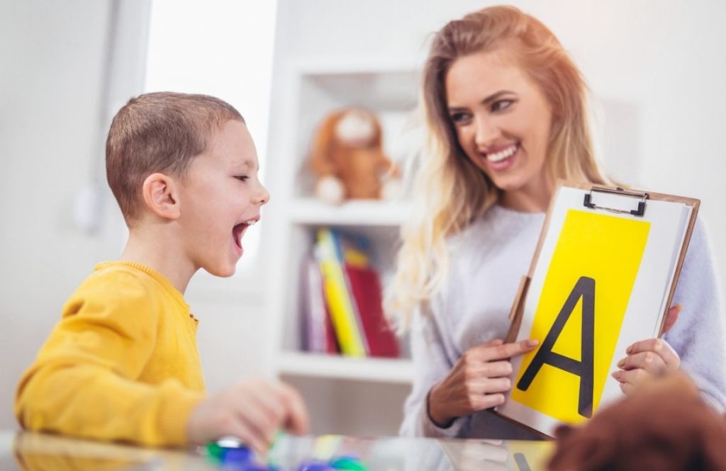 Une orthophoniste travaille avec un enfant sur la lettre A