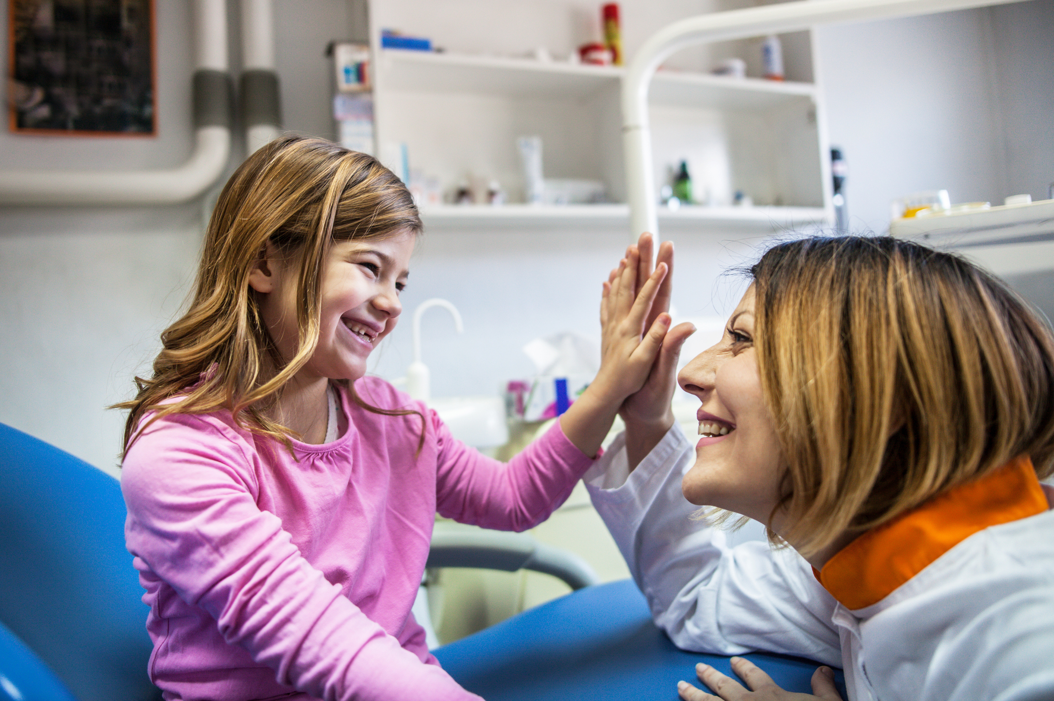 Enfant qui sourit et tape dans la main d'un docteur.