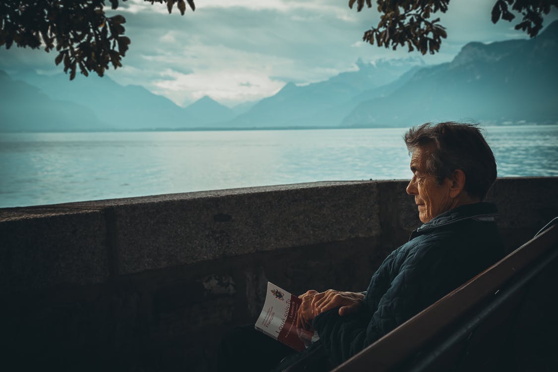 Un homme âgé assise face à un lac