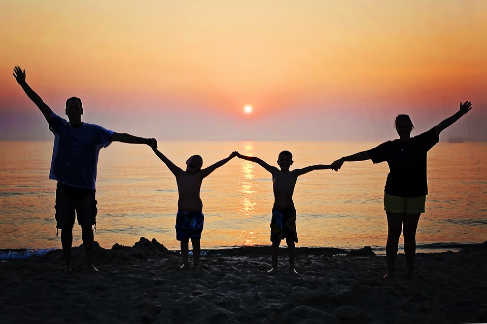 Une famille qui se tient par la main devant un coucher de soleil