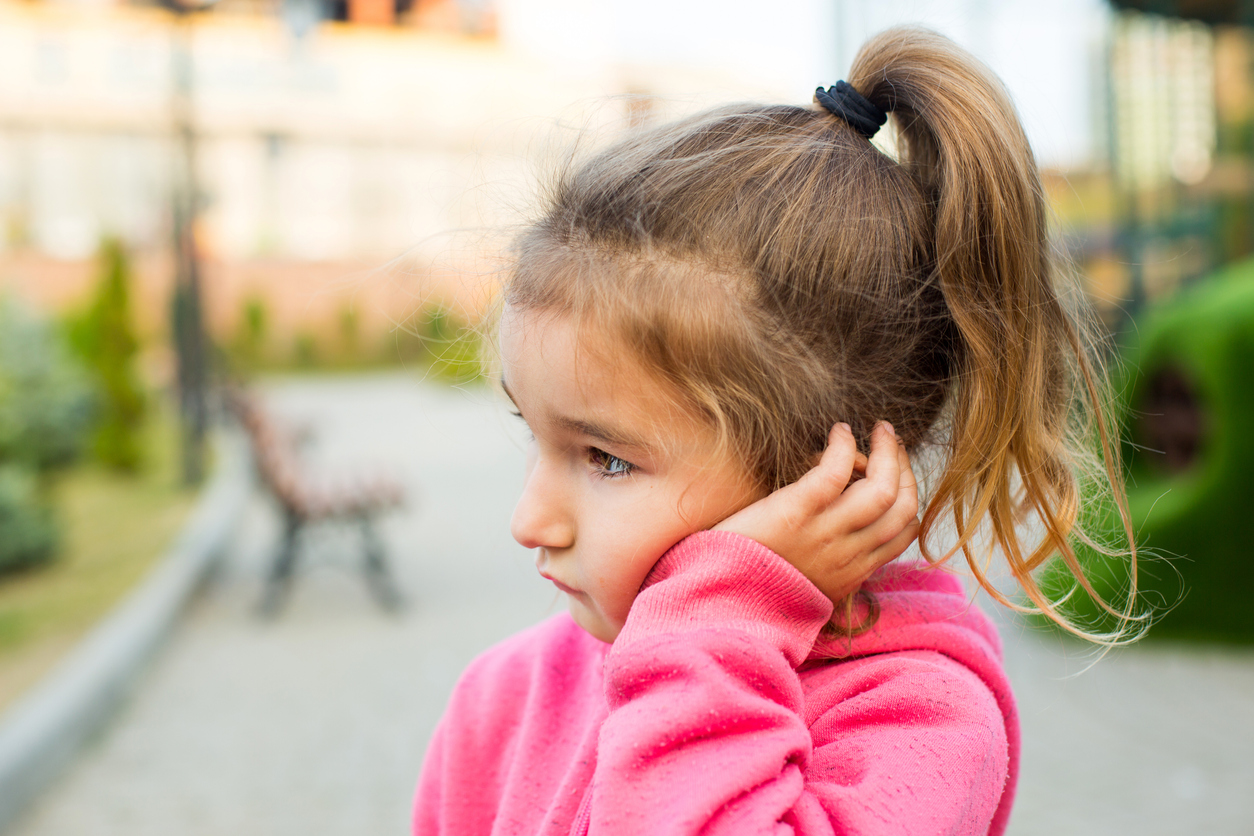 Une jeune fille se tient l'oreille