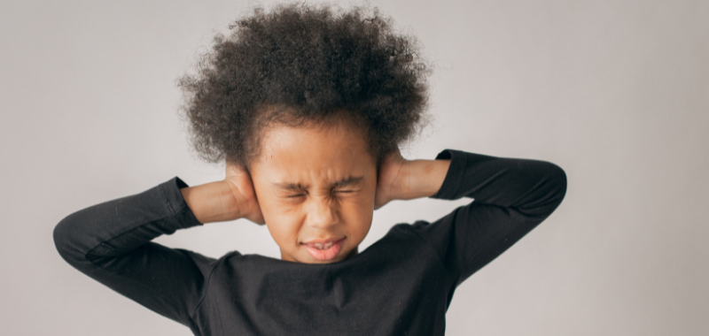 enfant hypersensible auditif avec ses mains sur les oreilles pour les boucher