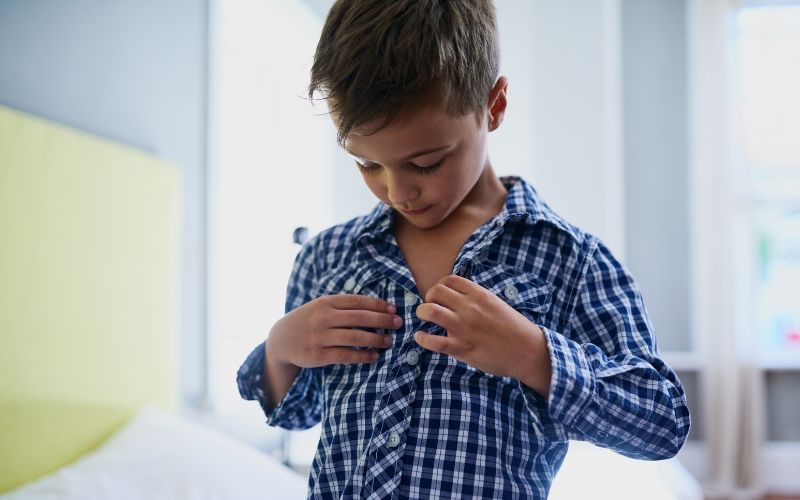 Enfant qui boutonne sa chemise seul