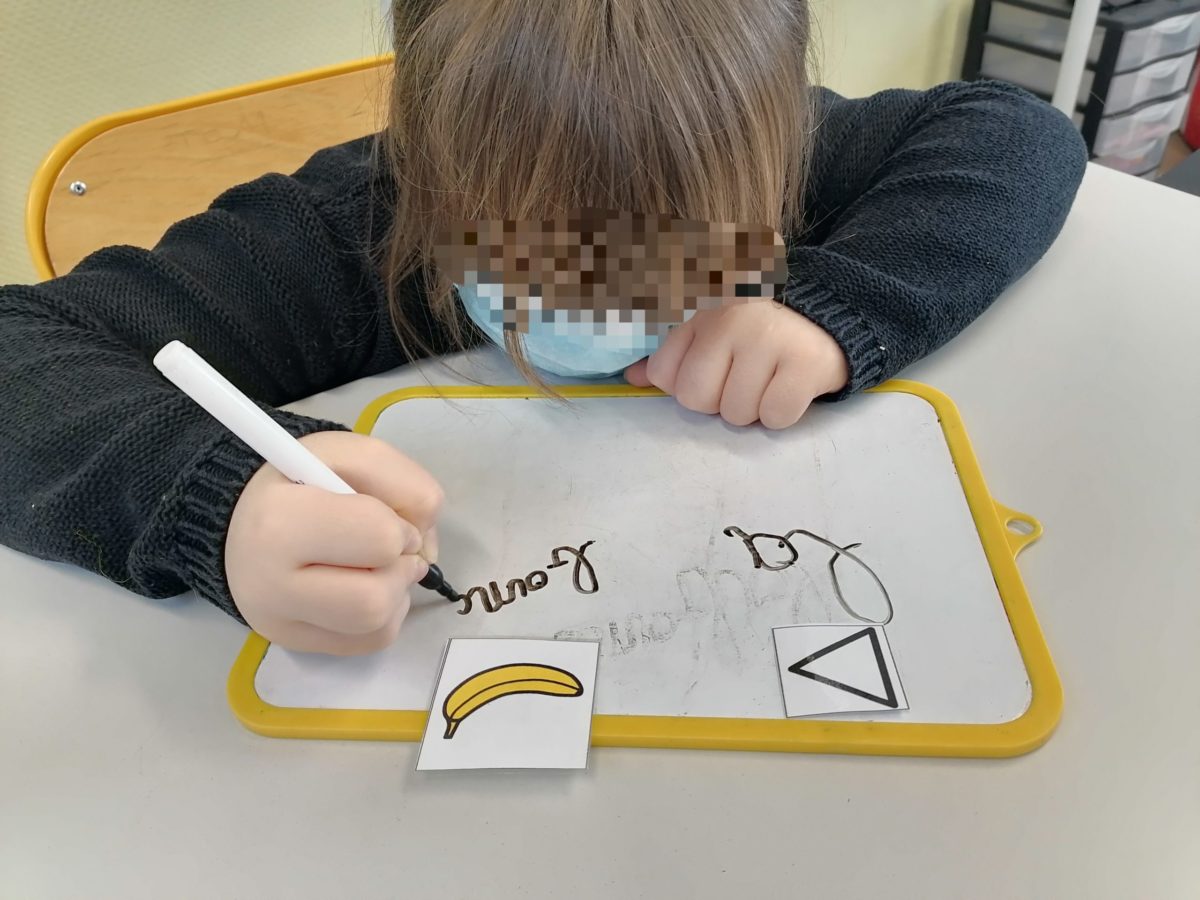 Un enfant écrit des mots à partir de pictogrammes