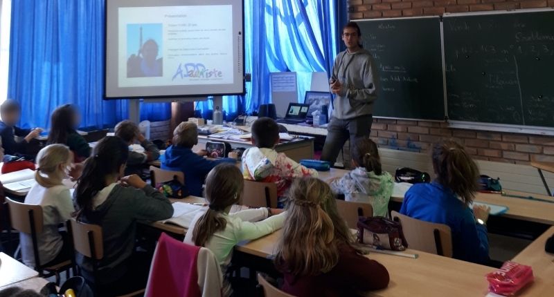 Tristan qui fait de la sensibilisation devant une classe à l'école primaire.