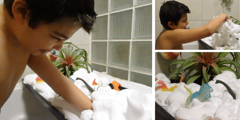 Milo dans son bain sensoriel qui joue avec de la mousse dans son bac d'exploration placé sur la baignoire.